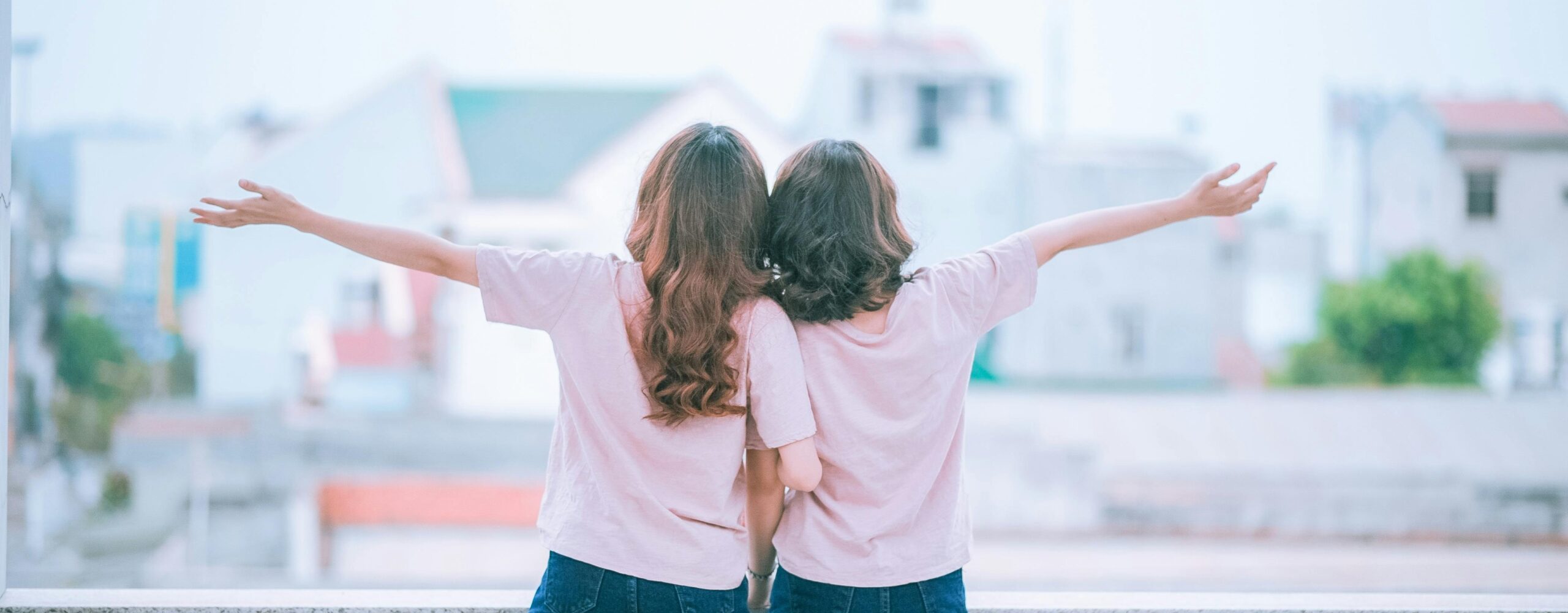 Two women embracing while facing a scenic backdrop, sharing joyful moments.