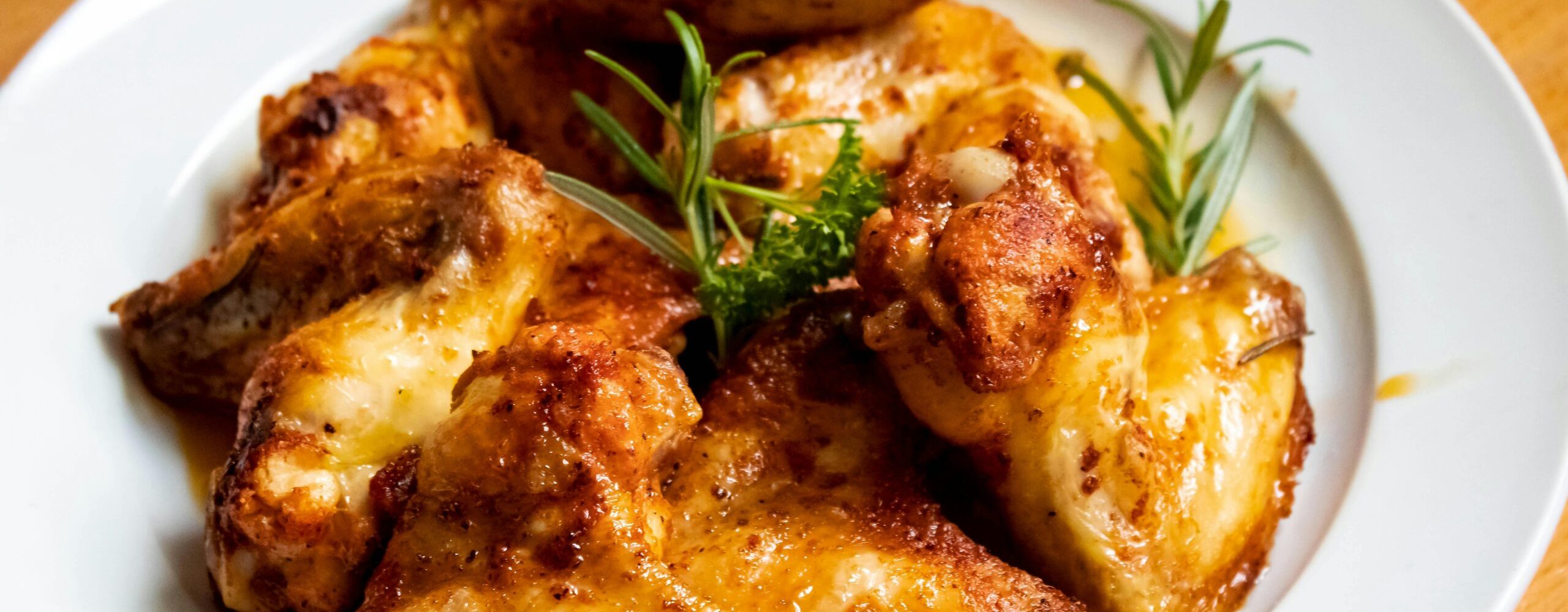 Golden-brown chicken wings garnished with fresh herbs, perfect for a tasty meal.